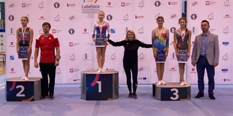Powiększ grafikę:  Ogólnopolska Olimpiady Młodzieży październik 2020.  Dominika na podium ze złotym medalem z finału skoku przez stół gimnastyczny.